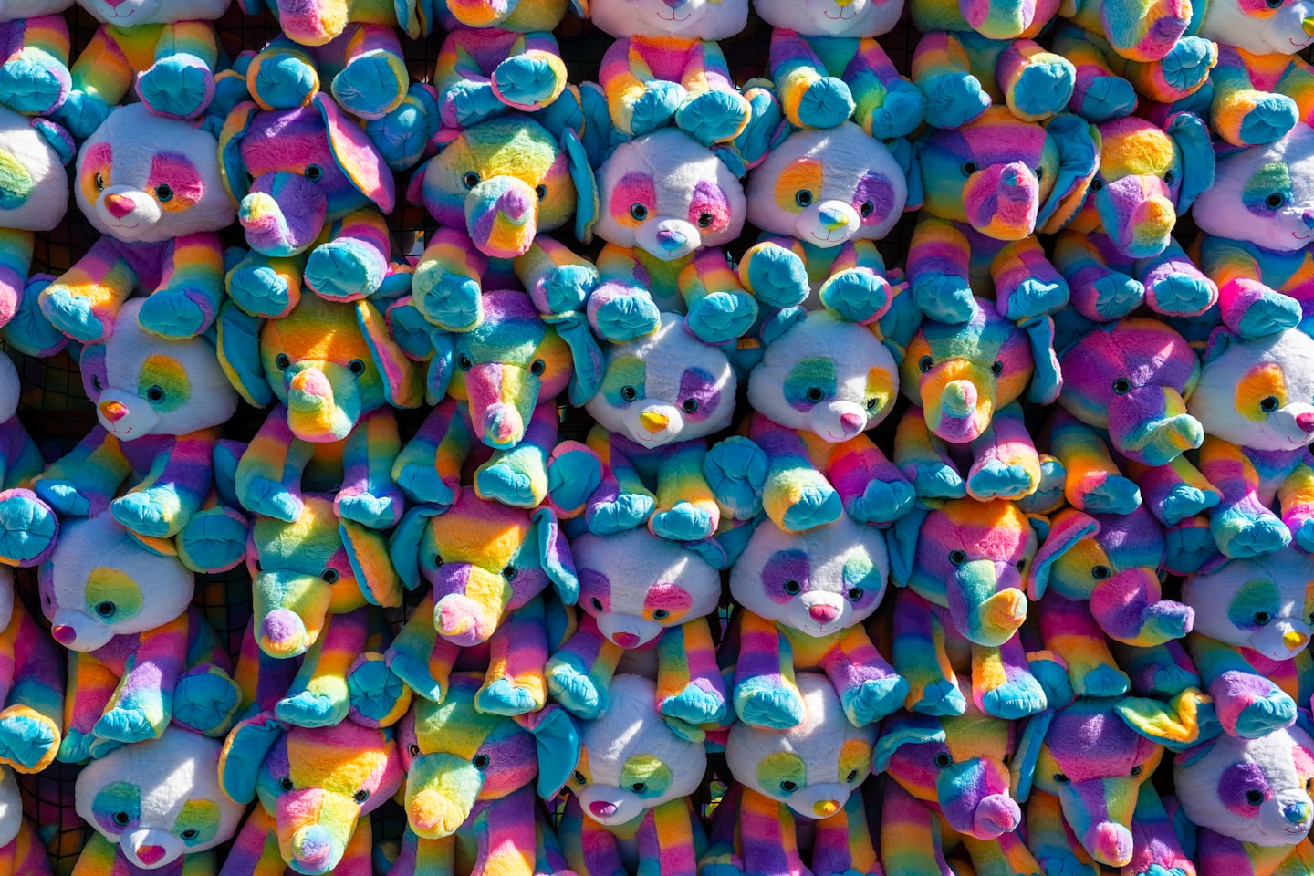 Colorful stuffed animals hanging together in a group.