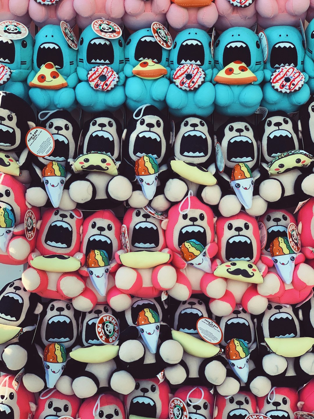 Colorful monster stuffed toys holding various food items on display.